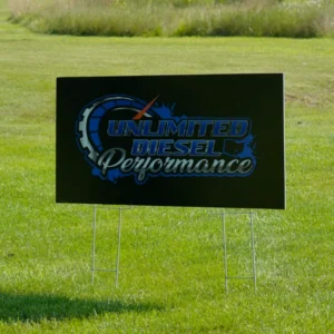 A black yard sign in a grassy field displays "Unlimited Diesel Performance" in blue and white text with a speedometer graphic, conveying power and speed.